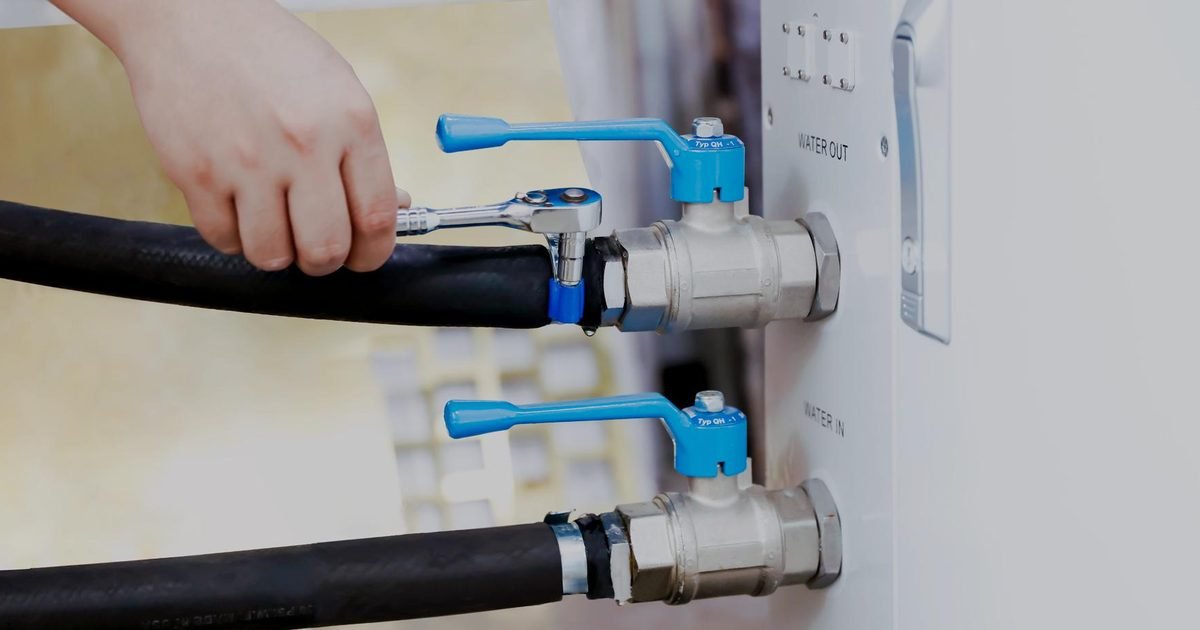 Hand an einer Kugelhahn-Verschraubung der Wasserführung einer Reinigungsanlage