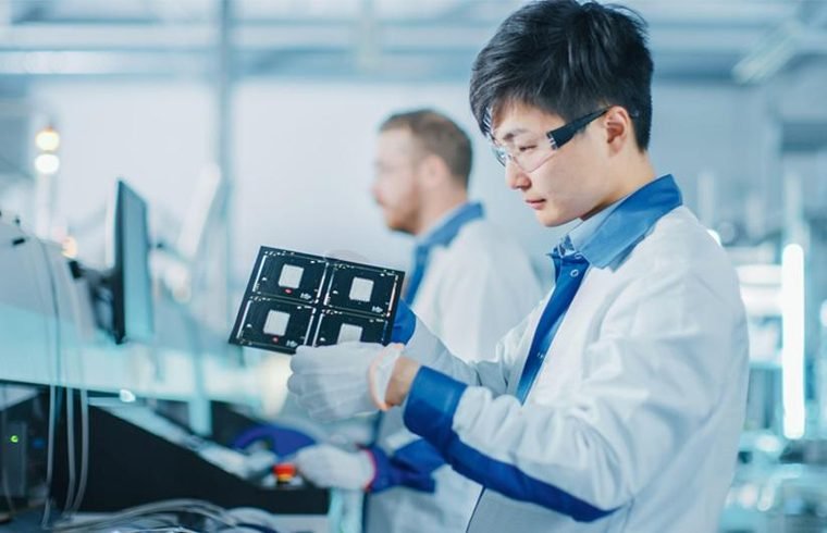Engineer inspecting an assembled printed circuit board under controlled lighting